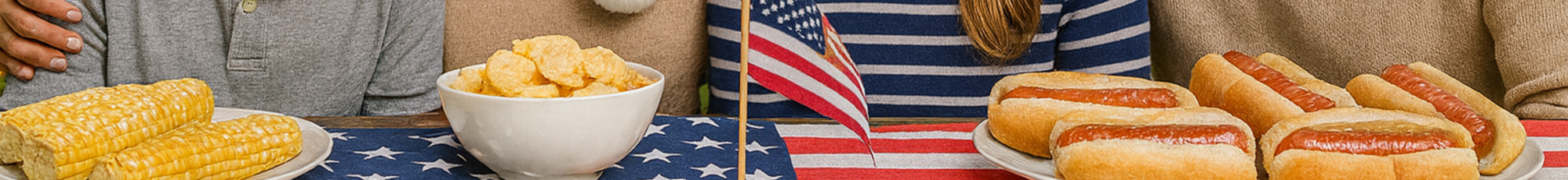 picnic with hotdogs, corn chips and a flag