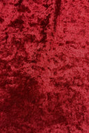 Close-up of rich red crushed Velvet fabric with a soft, shiny, textured surface.
