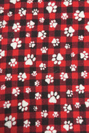 Red and black buffalo plaid fabric patterned with scattered white paw prints of various sizes.