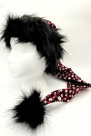 A mannequin head wearing a novelty Santa-style hat with shaggy black faux fur on top, a long red plaid fabric tail decorated with white paw prints, and a large black furry pom-pom at the end.