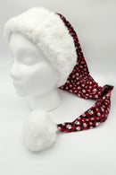 Red plaid Santa-style hat with white paw print pattern, featuring a fluffy white faux fur brim and large white pom-pom, displayed on a white mannequin head.