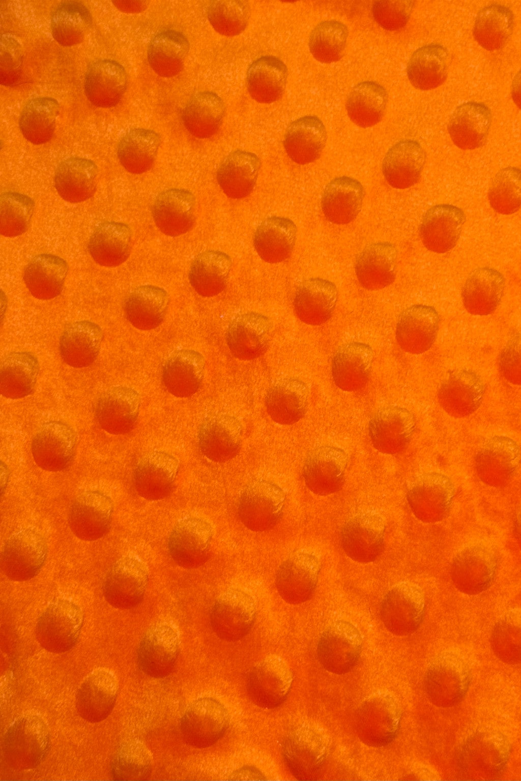 Close-up of bright orange fabric with a raised dotted texture, featuring evenly spaced circular bumps.