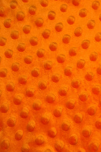 Close-up of bright orange fabric with a raised dotted texture, featuring evenly spaced circular bumps.