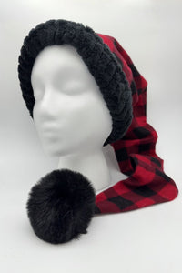 A mannequin head wearing a long red and black (buffalo) plaid Santa-style hat with a thick black faux-fur trim and a large black furry pom-pom at the end.