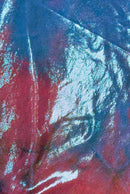 Close-up of iridescent fabric with a textured surface, reflecting pastel greens blues pinks and turquoise, creating a shimmering, metallic effect.