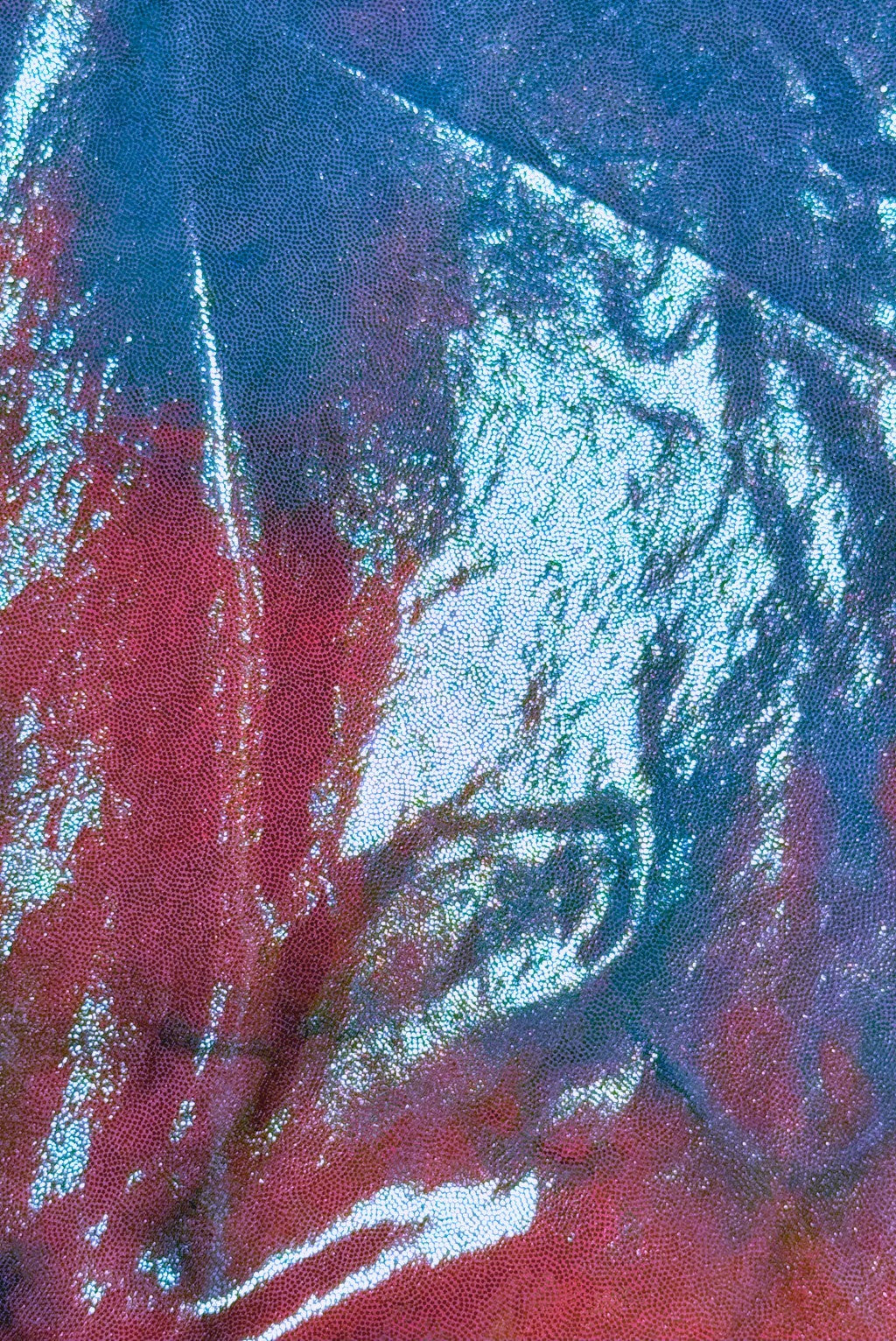 Close-up of iridescent fabric with a textured surface, reflecting pastel greens blues pinks and turquoise, creating a shimmering, metallic effect.