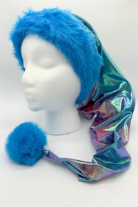 Mannequin head wearing a long, shimmering iridescent hat with a fluffy bright blue faux fur trim and matching blue pom-pom at the end.