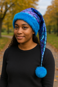 Woman in an autumn park wearing a handmade Shimmering Mermaid Scales Hat with blue faux fur trim and matching blue pom-pom.