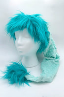A mannequin head with a short, spiky Teal trimmed Santa-style hat, soft textured tail-like extension ending in a fluffy Teal pom-pom, displayed against a white backdrop.