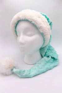 Light aqua blue minky Santa-style hat with raised dot texture, trimmed in white faux fur, and finished with a fluffy white pom-pom, displayed on a white mannequin head.