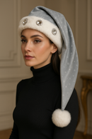 Elegant model indoors wearing a handmade silver Velvet hat with white fur trim, large sparkling rim jewels, star details, and a white pom-pom.