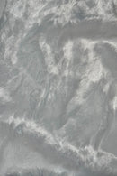 Close-up of a soft, shiny white faux fur fabric with a silky texture and light reflecting off its surface.”