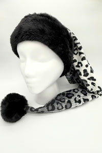 A mannequin head wearing a long, pointed winter hat with a thick black faux fur trim and pom-pom. The body of the hat is gray with a black leopard print pattern, extending down to one side.