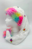 A fluffy white hat with a long tail, decorated with small colorful ice cream cone buttons. The hat has rainbow faux fur trim in bright shades of pink, yellow, green, and blue around the front edge and at the tip of the tail. The hat is displayed on a white mannequin head against a light background.
