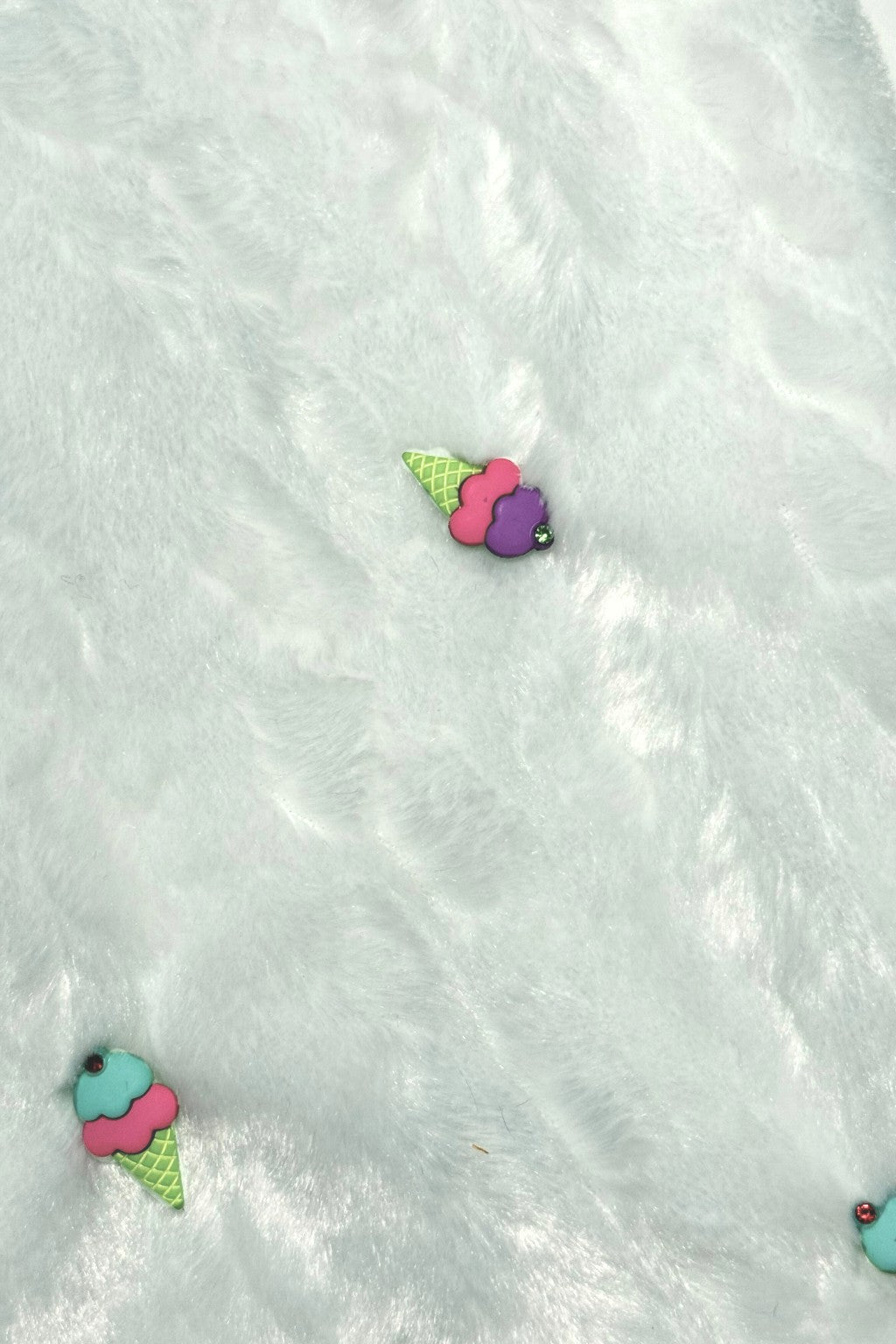 Light blue furry textured fabric with two small decorative patches shaped like colorful ice cream cones, one with purple and pink scoops and the other with turquoise and pink scoops, both with green cones.