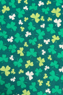 Patterned fabric with scattered shamrocks in various shades of green and white on a dark green background.