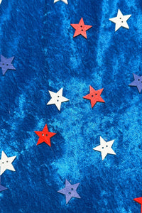 Pattern of red, white, and blue star-shaped buttons with two holes in the center, scattered across a shiny, textured royal blue fabric background.