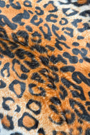 Close-up view of orange and black leopard print faux fur fabric, showing soft texture and bold spotted pattern.