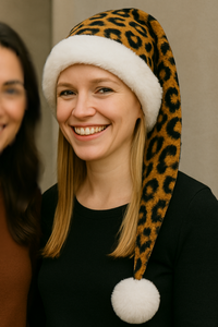 An adult model standing near a friend wearing a brown leopard print hat with white trim and white pom-pom.