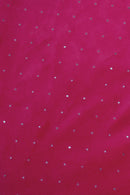 A close-up of a bright pink fabric with small, evenly spaced silver rhinestones scattered across the surface, creating a sparkling effect.