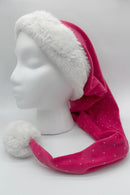 Pink Santa-style hat with small silver dots, featuring a fluffy white faux fur trim and a large white pom-pom at the tip, displayed on a white mannequin head against a plain background.