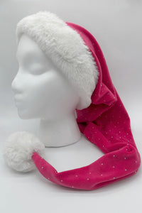Pink Santa-style hat with small silver dots, featuring a fluffy white faux fur trim and a large white pom-pom at the tip, displayed on a white mannequin head against a plain background.