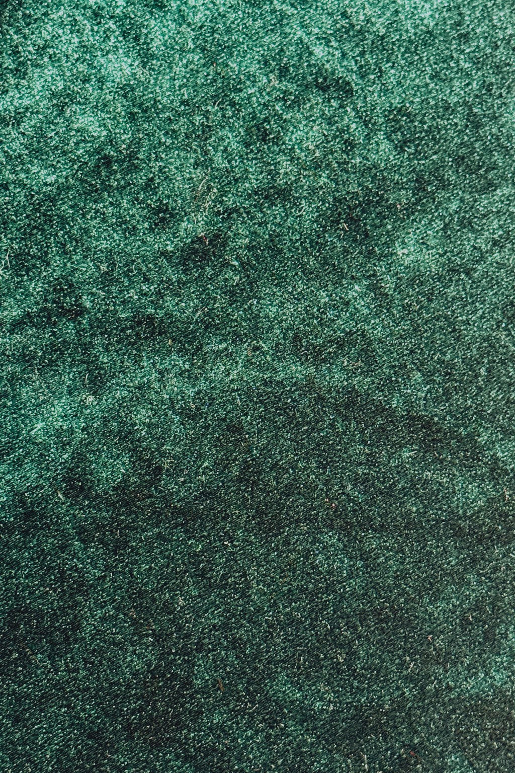 Close-up of dark green Velvet fabric with a wavy, iridescent sheen.