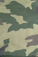 Close-up of fabric with a camouflage pattern in shades of green, brown, and beige. The irregular shapes blend together to create a classic military-style design.
