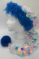 A Santa-style hat with bright blue faux fur trim, a long tail of iridescent pastel sequins, and a fluffy blue pom-pom displayed on a white mannequin head.
