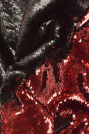 Close-up of reversible sequin fabric with red and black sequins, reflecting light to create a shiny, textured surface.