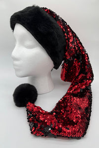 A mannequin head wearing a festive Santa-style hat with a black faux fur brim and a long, pointed body covered in shiny red and black sequins, ending in a black faux fur pom-pom.