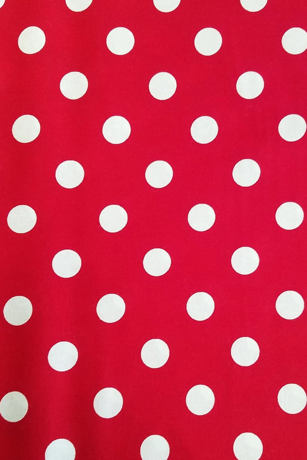 Red fabric background with evenly spaced white polka dots in a regular grid pattern.