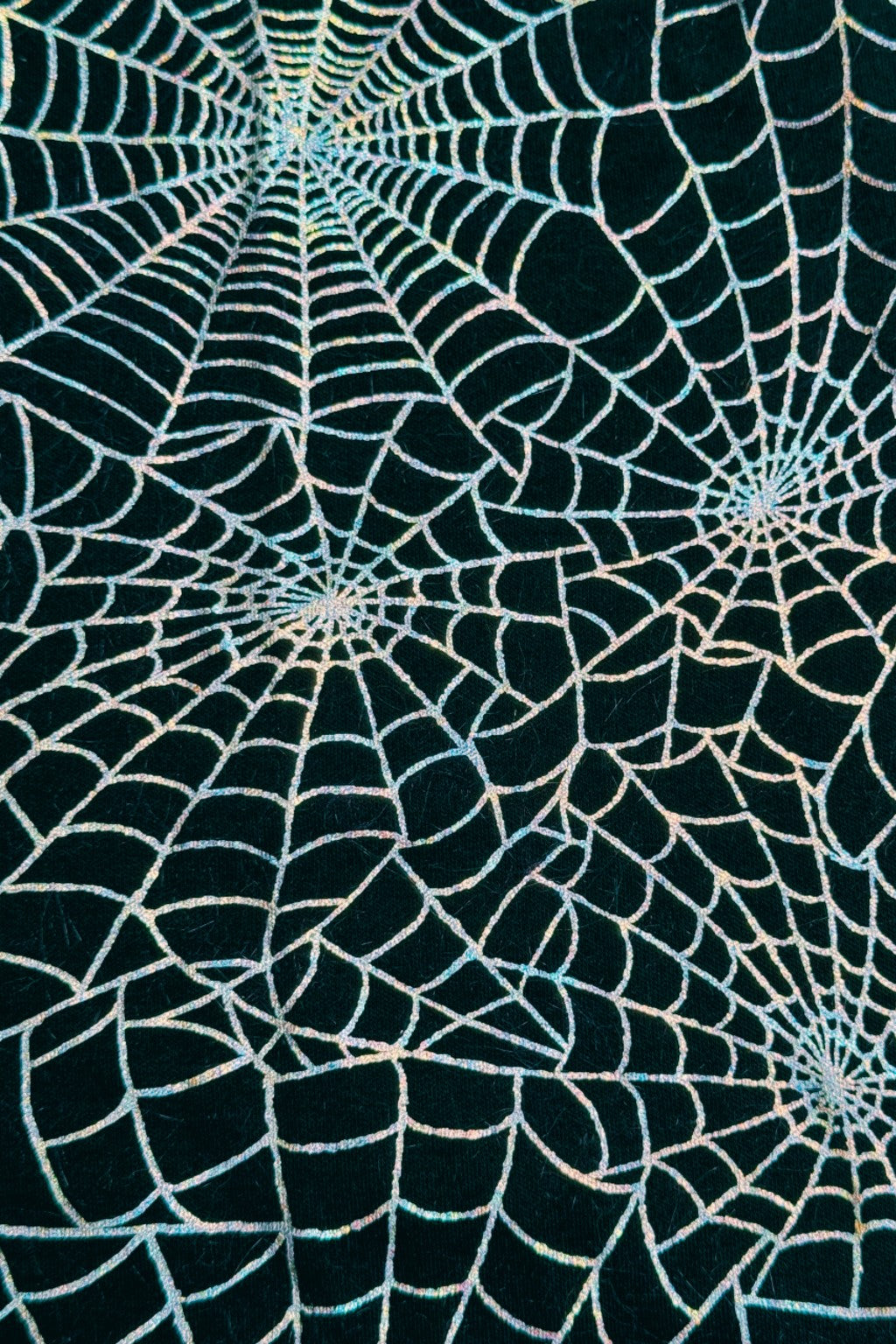 Black fabric patterned with multiple shimmering silver spiderweb designs.