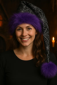 Woman wearing a spiderweb hat with a purple pom-pom against a dark background