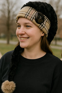 Adult model wearing a handmade black velvet hat featuring Burberry plaid trim, large button, and tan pom.