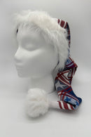 A white mannequin head wearing a long festive hat with a fluffy white faux fur brim and pom-pom. The hat features a red, white, and blue plaid design with star patterns.