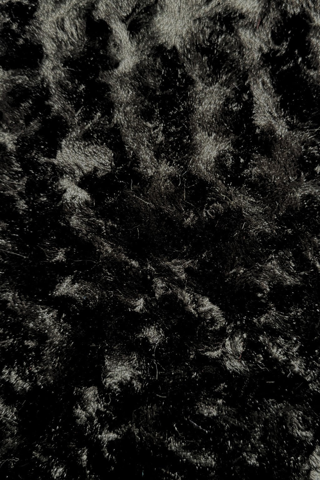Close-up view of a black panne Velvet fabric.  The panne Velvet is soft, shiny, and has slightly wavy pattern reflecting light.