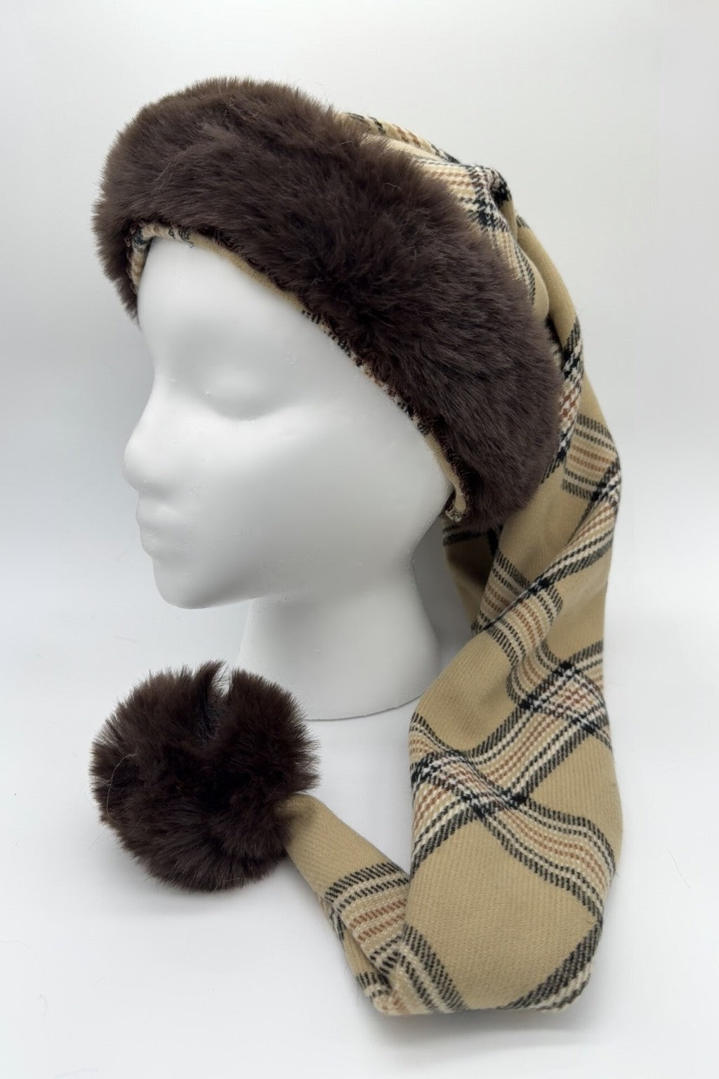 Mannequin head wearing a Burberryg tan plaid hat with dark brown faux fur trim and a matching fur pom-pom at the tip.