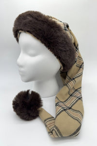 Mannequin head wearing a Burberryg tan plaid hat with dark brown faux fur trim and a matching fur pom-pom at the tip.